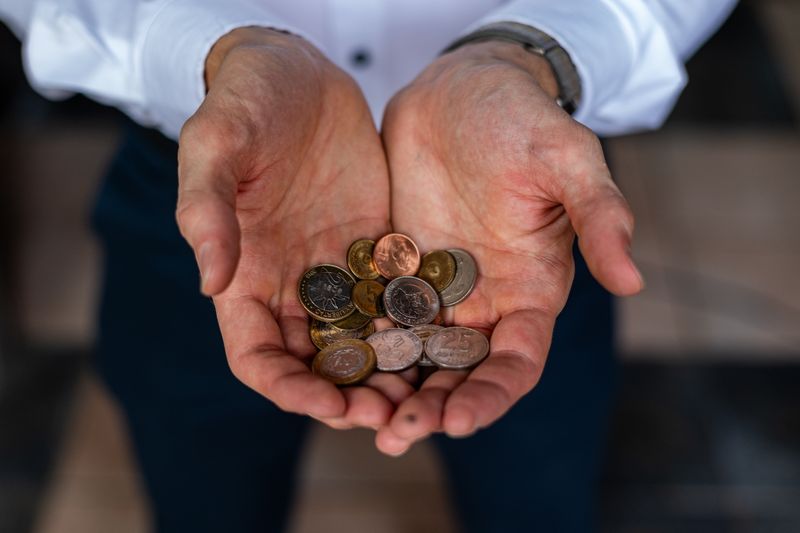 Closeup of hands holding various Argentine peso coins, symbolizing currency and finance in Argentina.