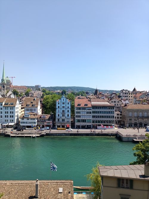 Free A picturesque view of Zurich's historic waterfront with charming buildings along the river under a clear blue sky. Stock Photo