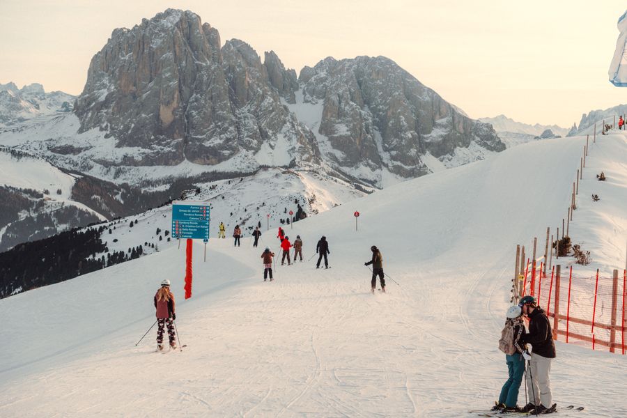 Skiers on a piste in the Italian Dolomites under a blue sky