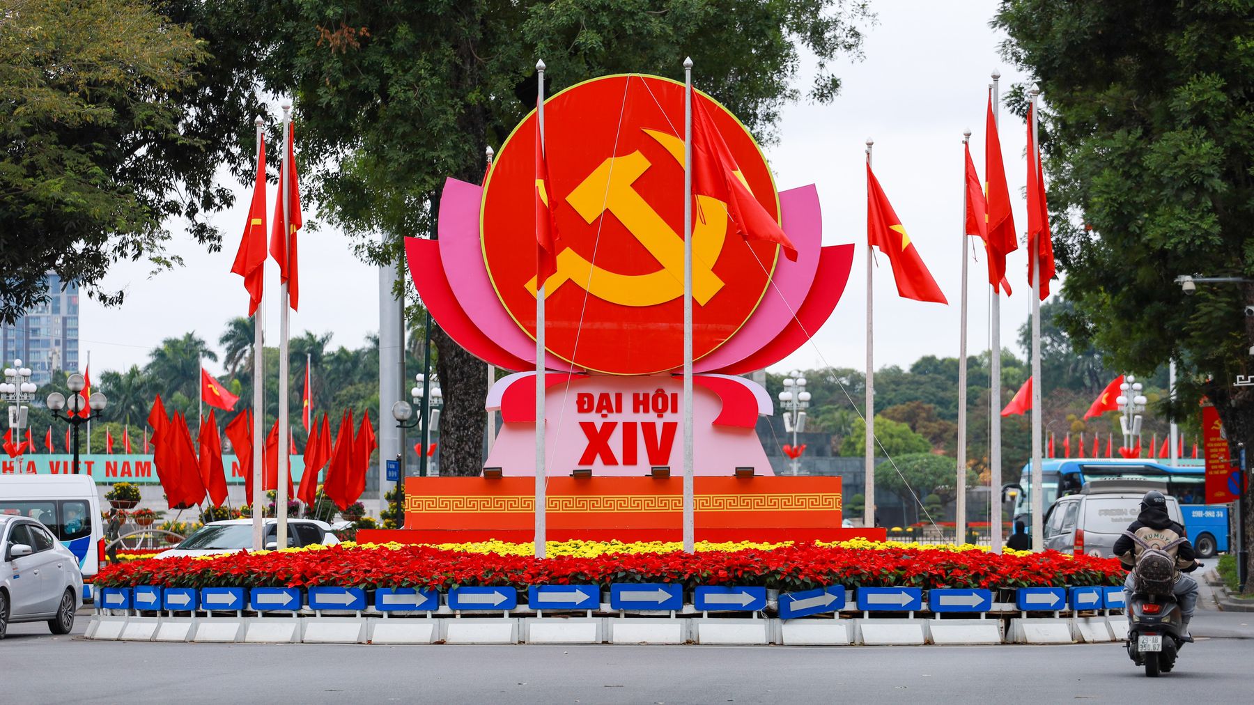 Iconic Communist symbol with flags in a Hà Nội city roundabout, vibrant display of national pride.