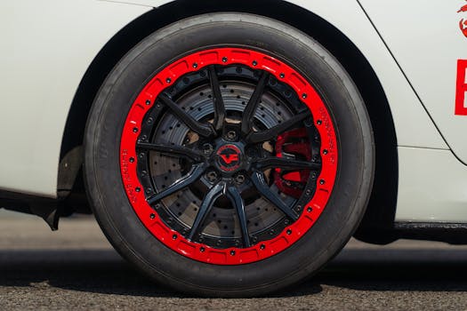 Detailed view of a stylish car wheel featuring a vibrant red and black rim on a white vehicle.