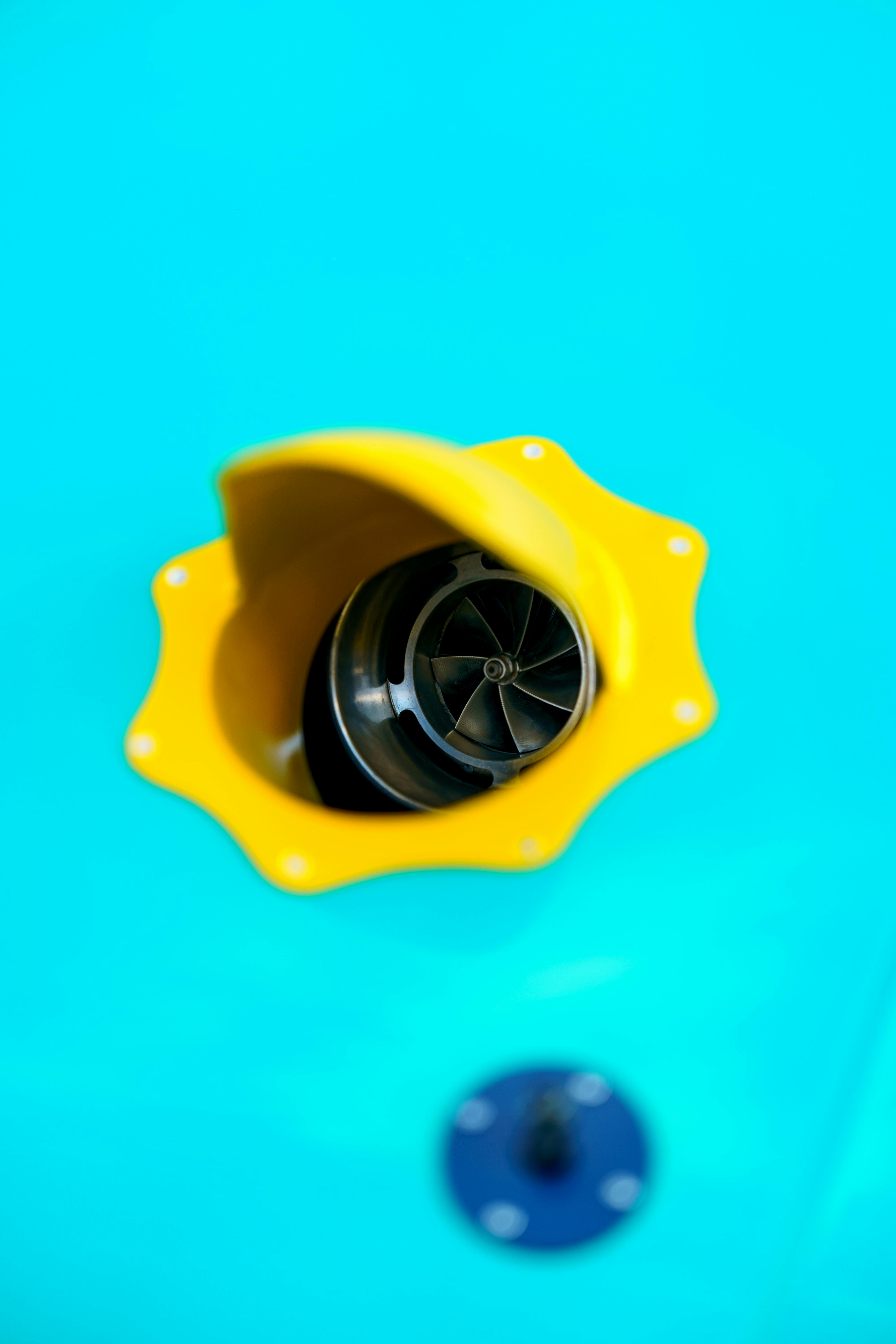 Bright close-up of a yellow turbine vent on a vibrant blue background, highlighting industrial design.