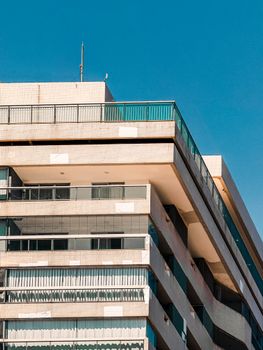A modern high-rise apartment building with geometric design and blue skies. Perfect for architecture and urban lifestyle themes.