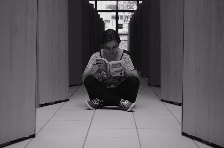 Woman Sitting On Floor Tile While Reading A Book