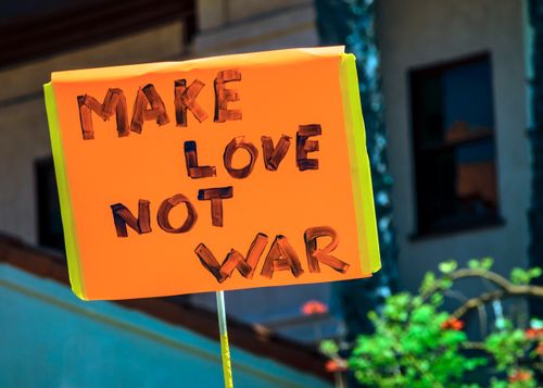 Free Bright orange protest sign in daylight with 'Make Love Not War' message advocating peace. Stock Photo