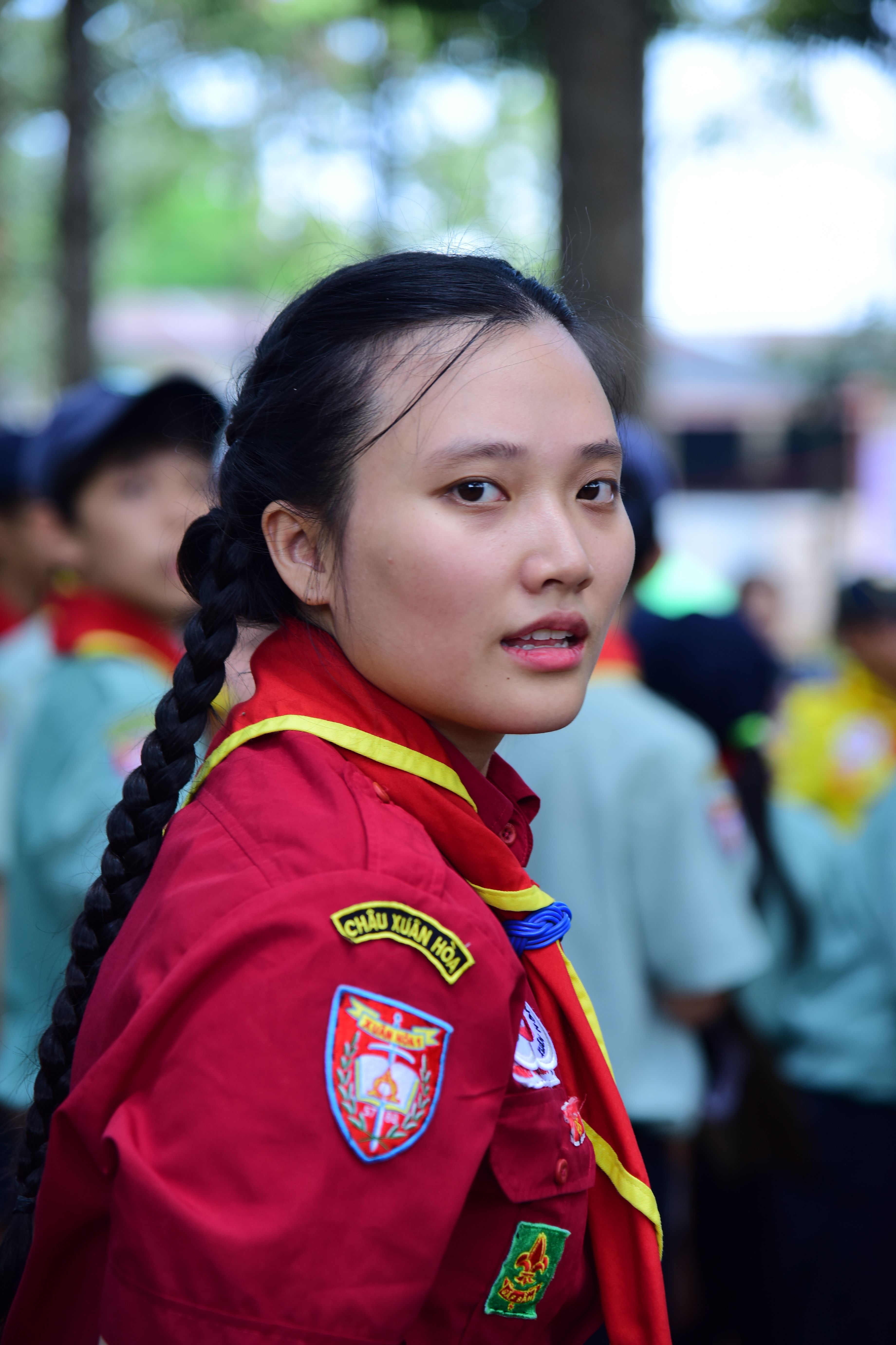 A young scout in a vibrant red uniform stands outdoors, looking back.