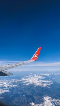 Scenic view from airplane window showcasing snowy mountains under vibrant blue sky.