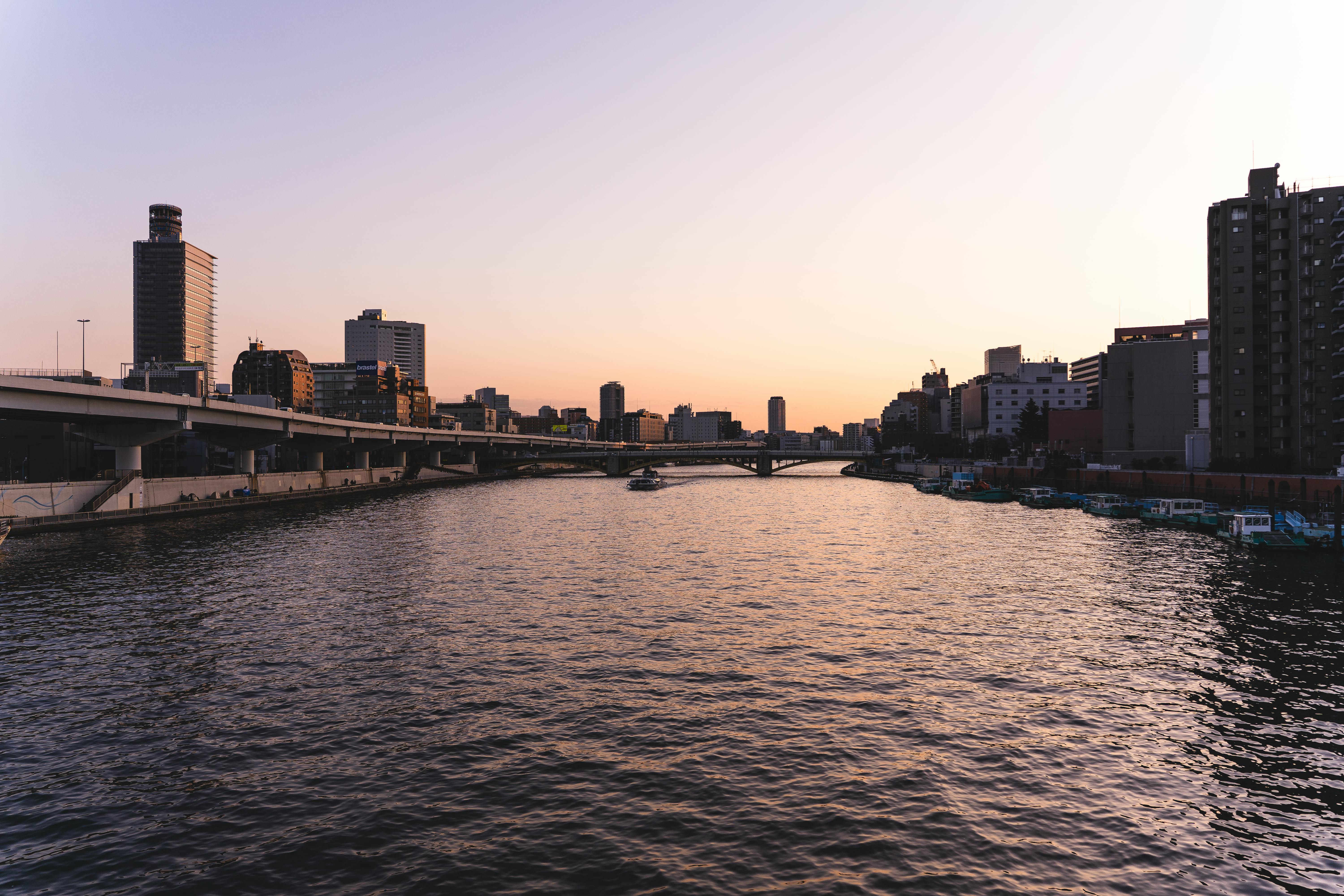 Scenic view of Tokyo's skyline and Sumida River at sunset, showcasing the city's architecture and tranquil waters.