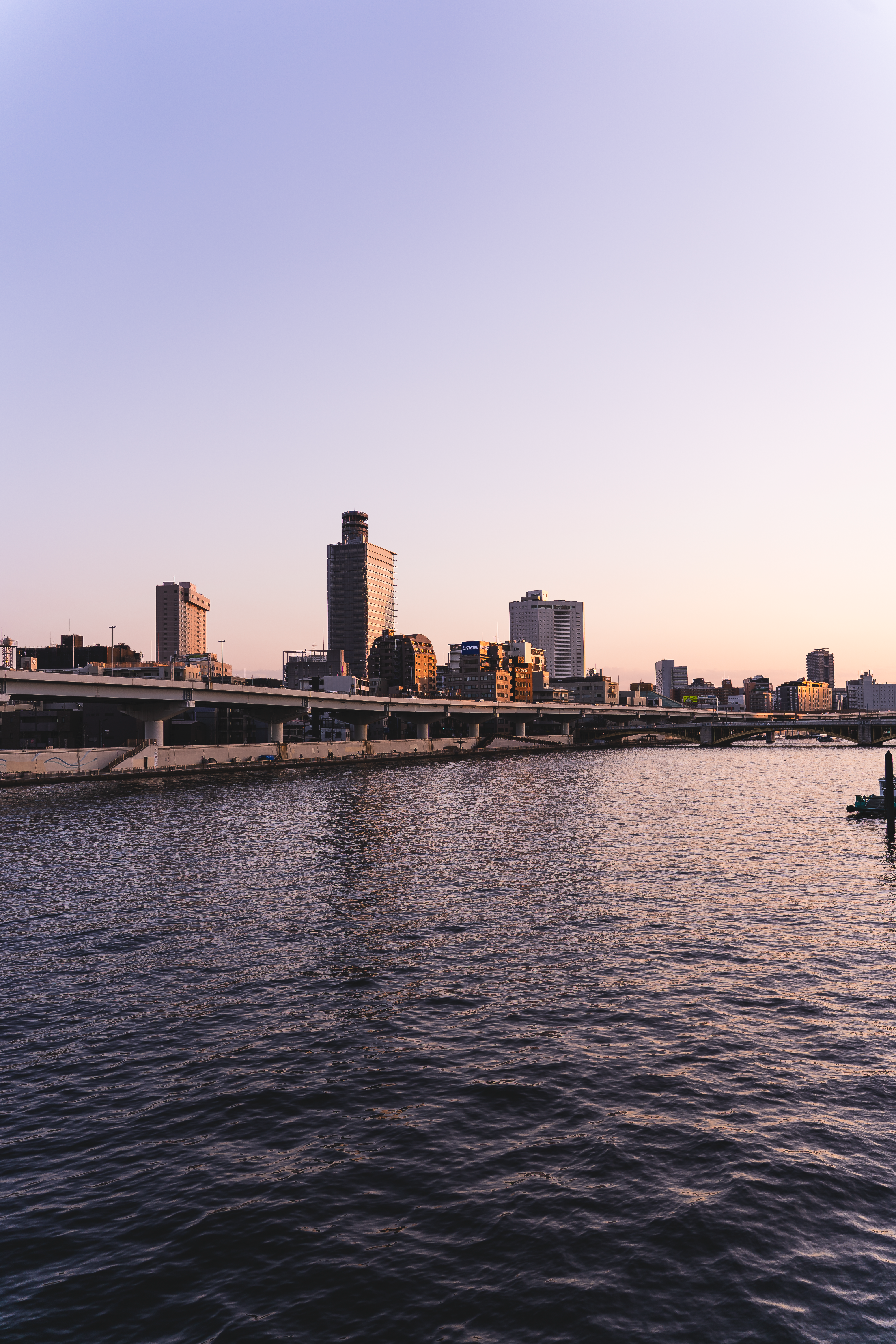 Peaceful sunset view over Sumida River with Tokyo skyline, showcasing modern architecture.