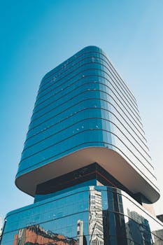 从低角度拍摄，一座现代摩天大楼的玻璃立面映衬着清澈的蓝天