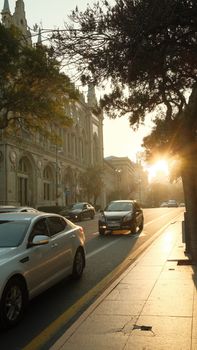 A picturesque evening view of a busy street in Baku, Azerbaijan, illuminated by the setting sun.