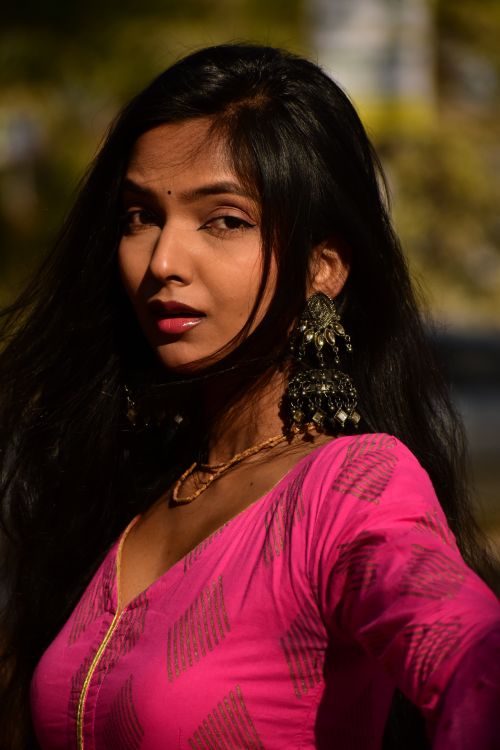 Free Portrait of a woman wearing a pink traditional dress with ornate earrings. Stock Photo
