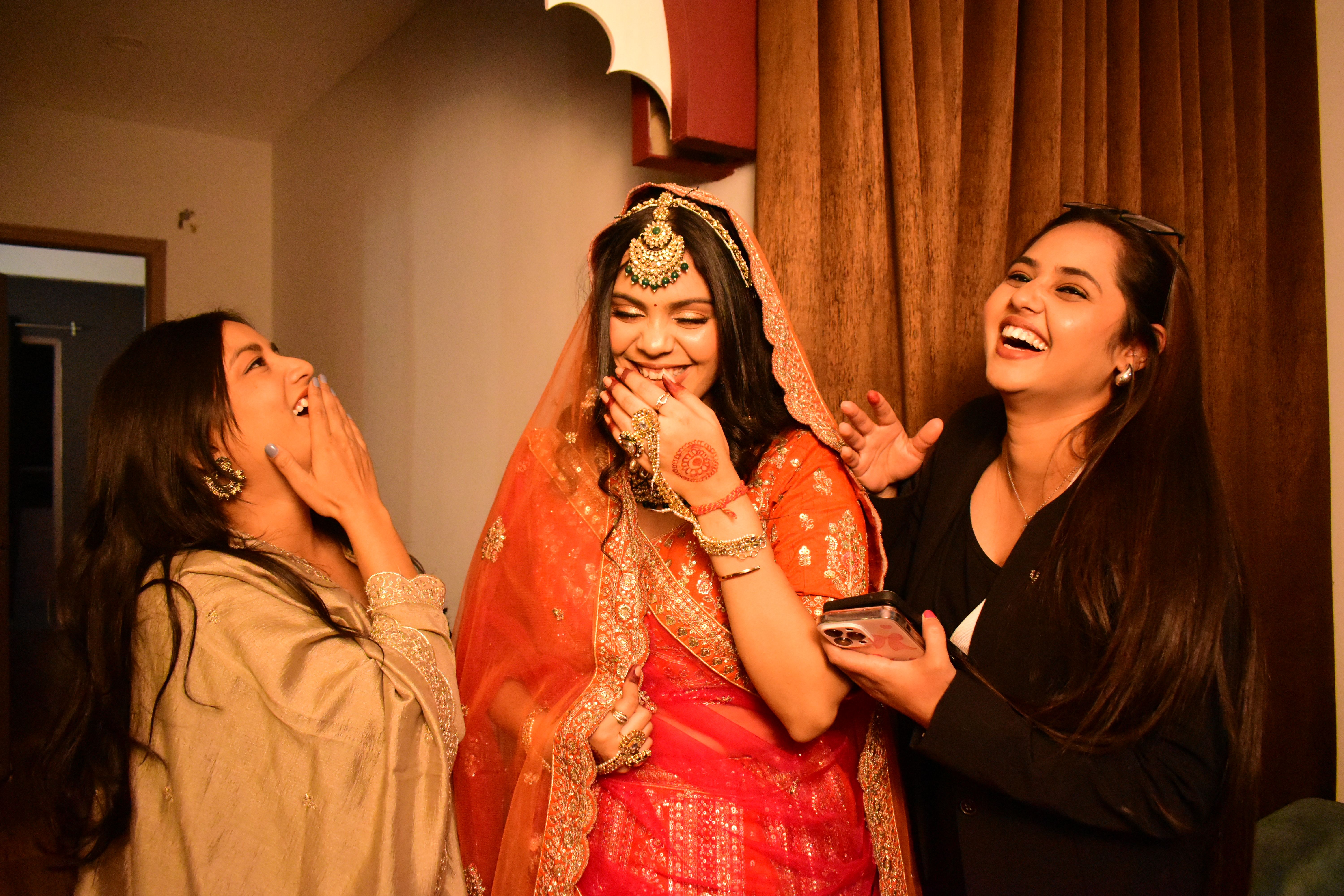 high-end wedding DJ Cairo — Three young women celebrating at an Indian wedding in vibrant attire and joyous mood.