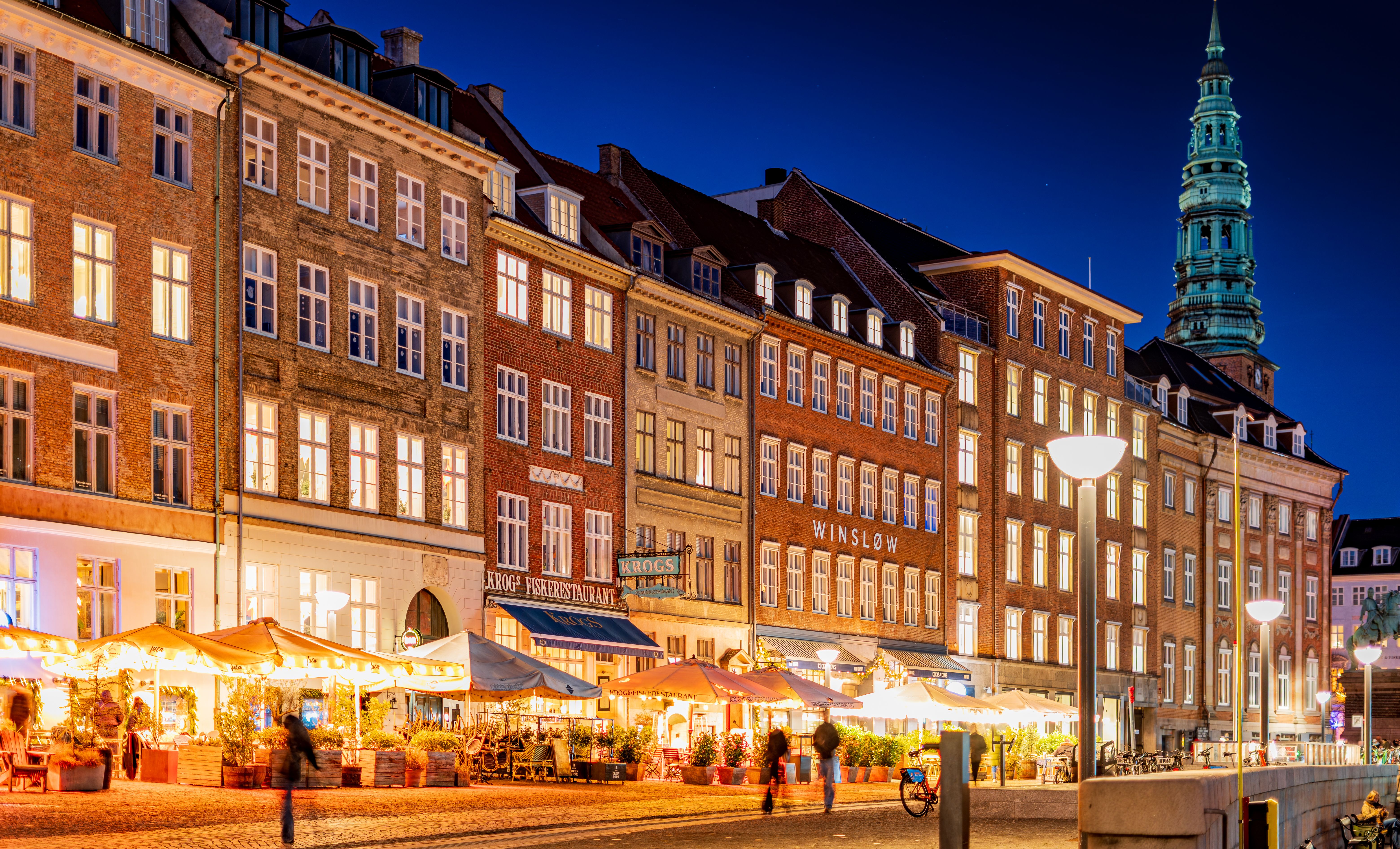 Cozy evening view in København's lively historic district with bright cafes and classic architecture.