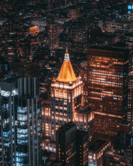 A breathtaking aerial view of New York City skyscrapers at night with glowing city lights.