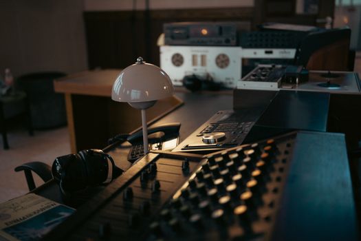 A cozy, dimly lit vintage recording studio with mixing consoles and equipment.