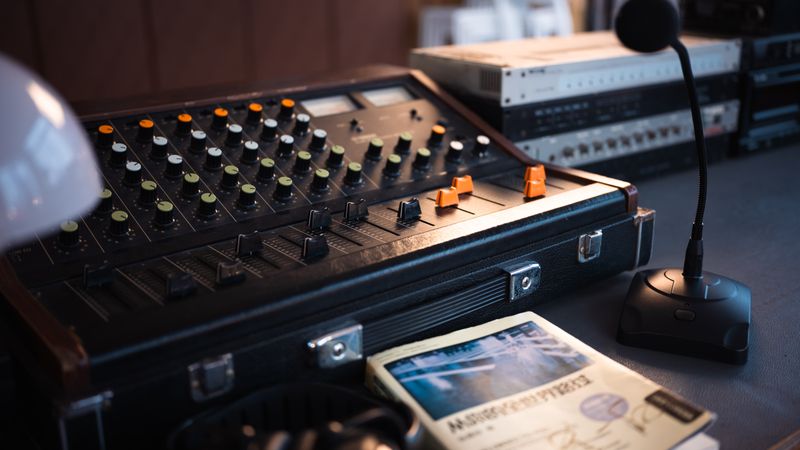 Close-up of a vintage audio mixer with a microphone and recording equipment on a desk.