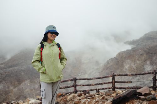 Free Female hiker amidst misty volcanic terrain in West Java, Indonesia, wearing adventure gear. Stock Photo