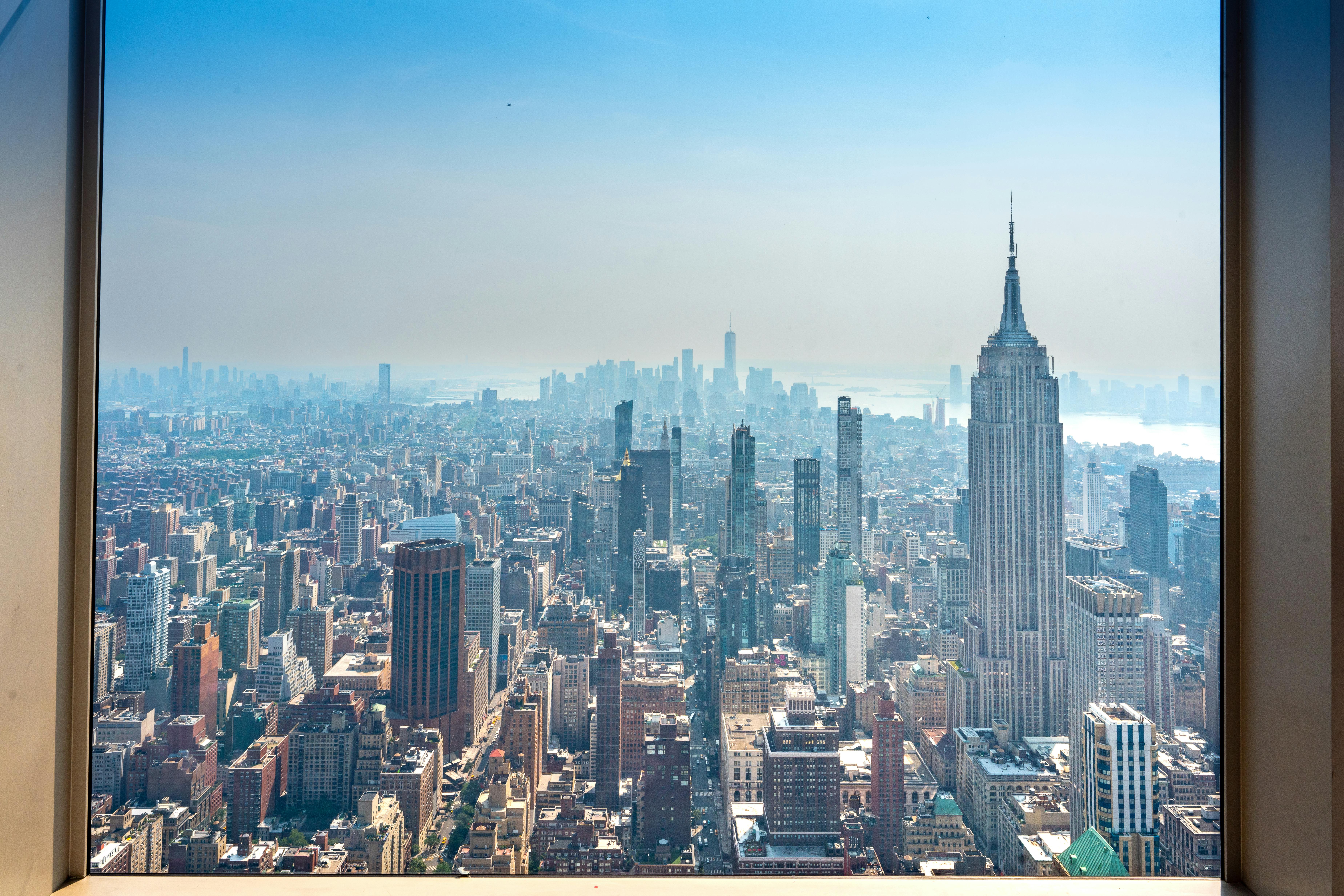 A breathtaking view of New York City skyline featuring the iconic Empire State Building on a clear day. - Nueva York