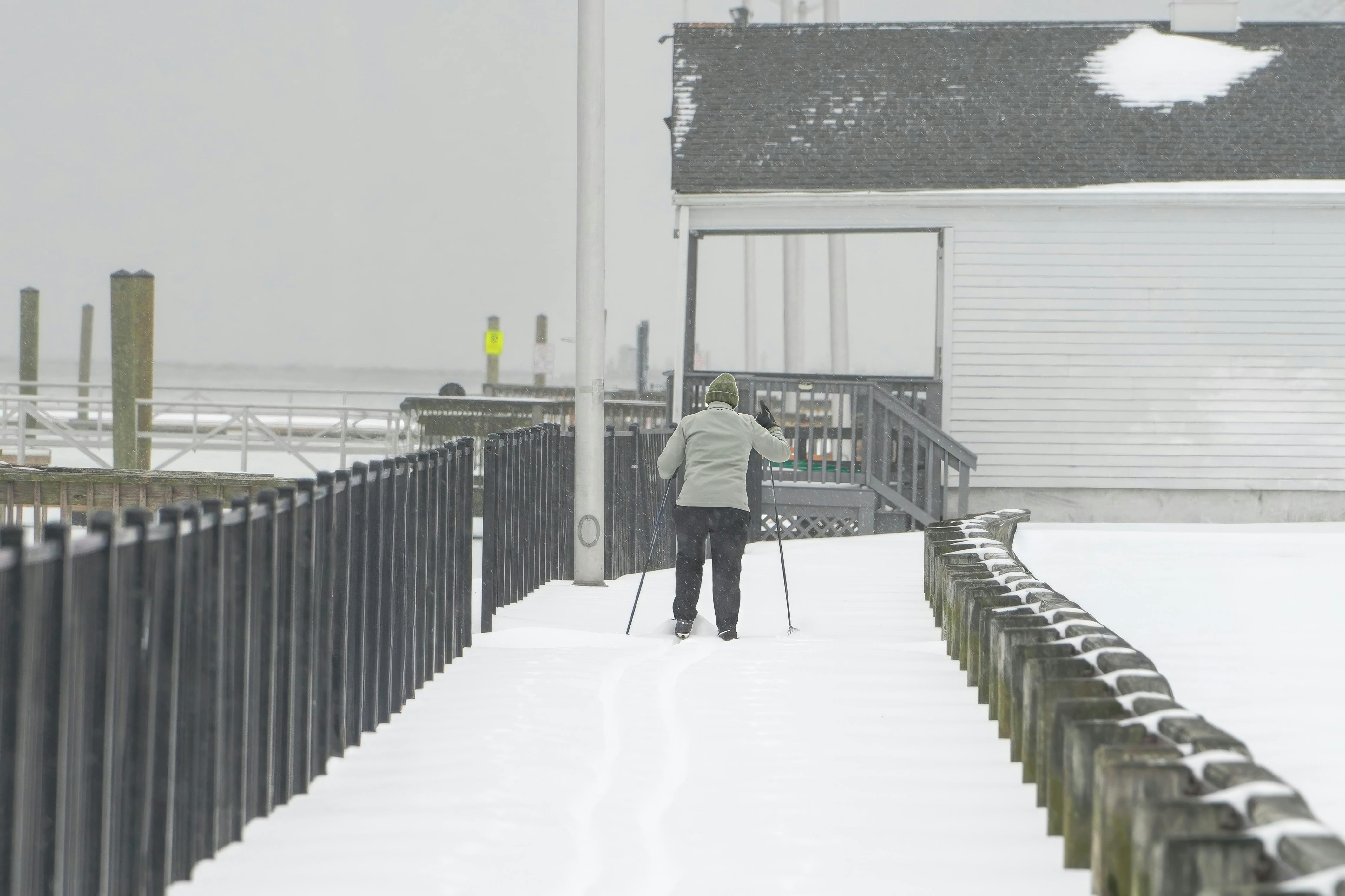 Skier enjoying cross-country skiing on a snowy urban path by the waterfront.