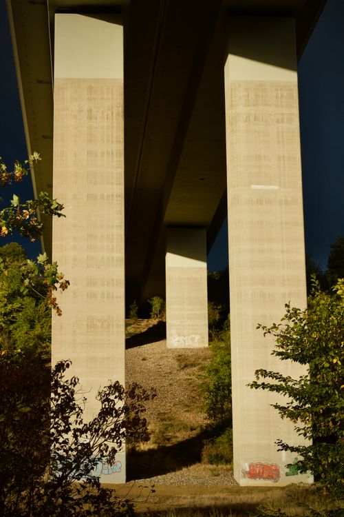 Free A detailed close-up of a bridge's supporting pillars displaying urban graffiti art. Stock Photo