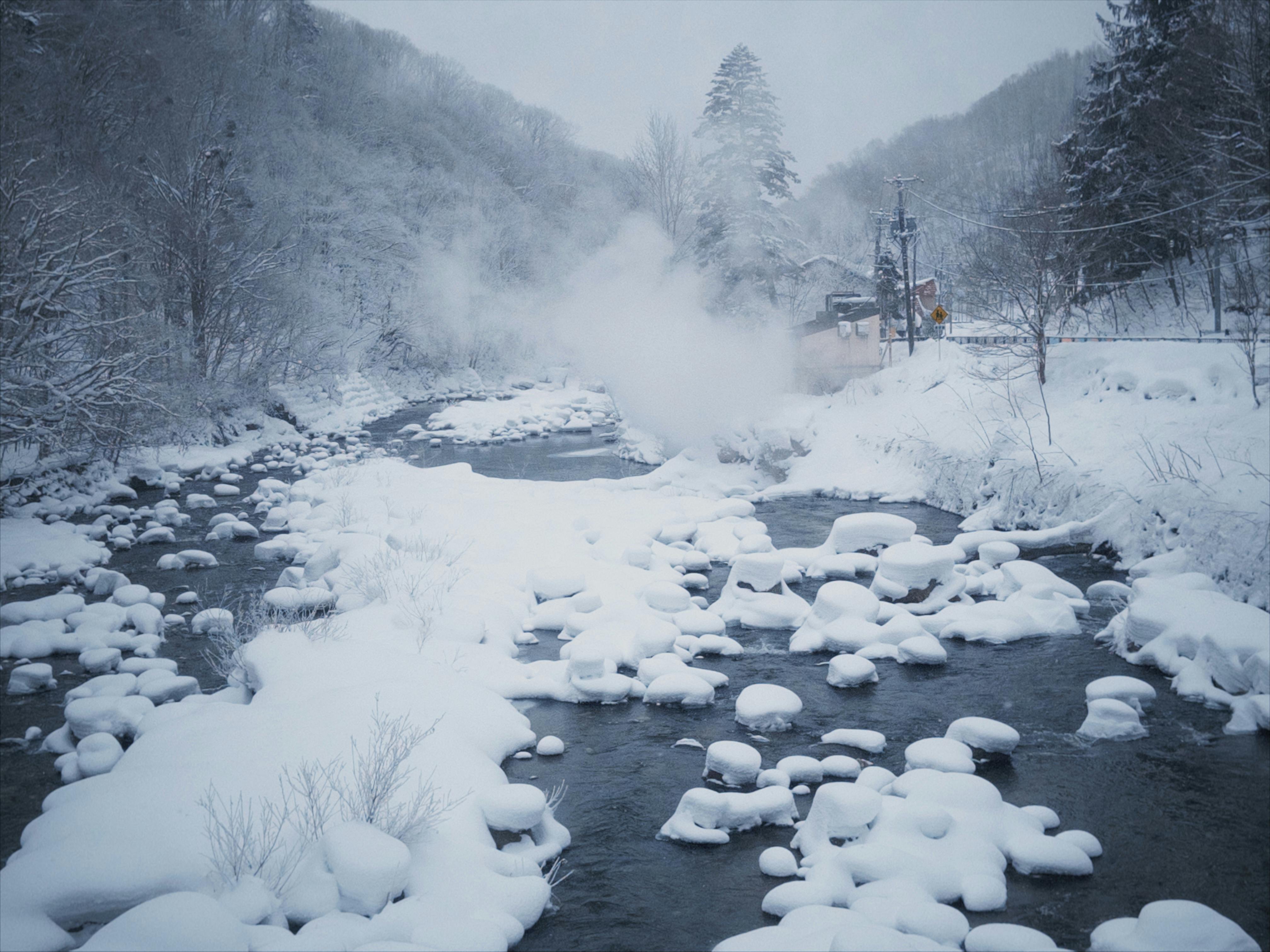 Steaming volcanic vents and sulfurous pools of Jigokudani at sunrise with wooden boardwalk in Hokkaido