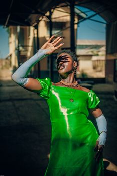 Stylish woman in a vibrant green dress poses dramatically outdoors.