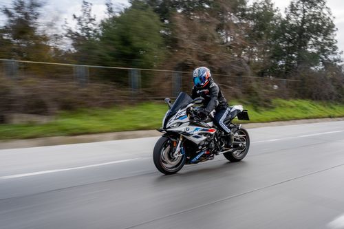 Free A motorcyclist in full gear speeding on an open road amidst a natural landscape. Stock Photo