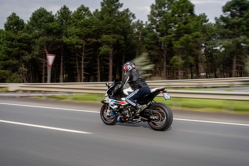 Free A motorcyclist speeds down the highway, surrounded by lush greenery. Captured in motion. Stock Photo