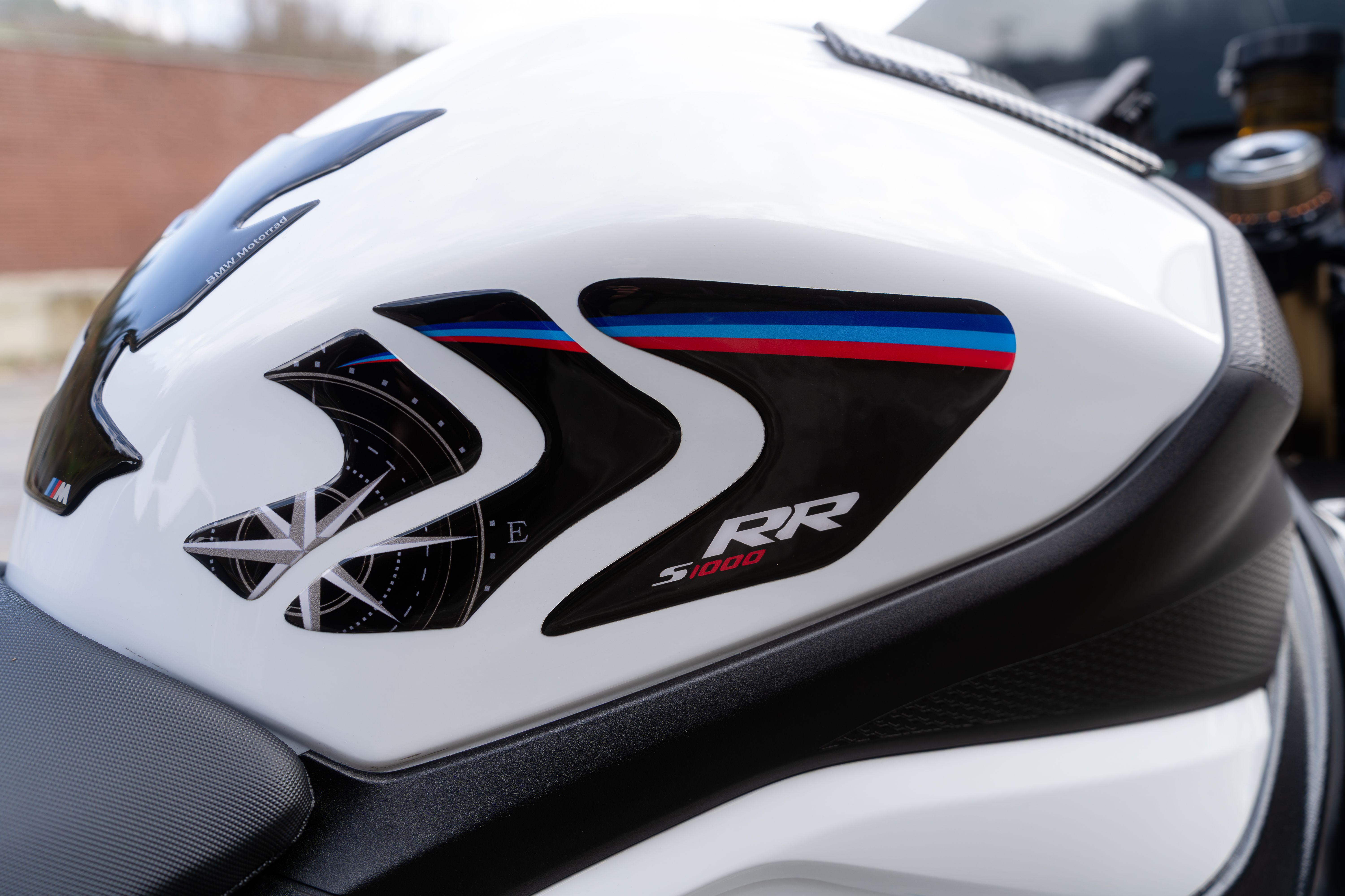 A detailed view of a white motorcycle tank with stylish decals and branding.