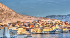 这座白雪皑皑的海边小镇充满活力，冬日场景迷人，房屋色彩缤纷