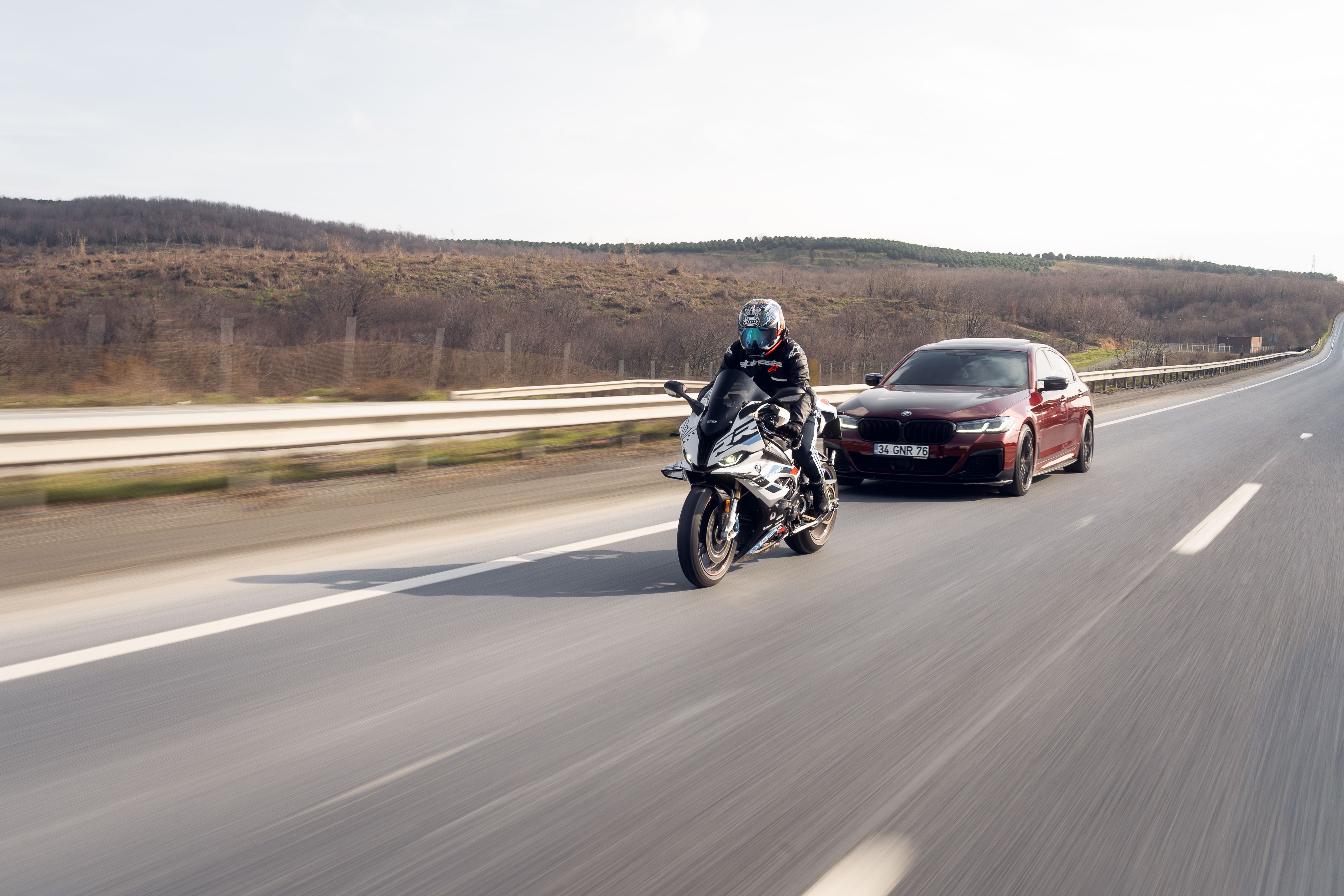 Dynamic shot of a motorcycle and car on a scenic highway.