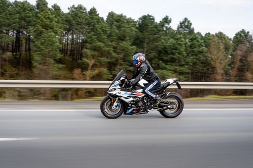 Free Motorcyclist riding through a scenic forest highway at high speed. Stock Photo