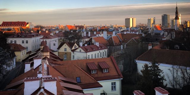 Stunning aerial view of Tallinn's Old Town with red rooftops and modern skyline at sunset.