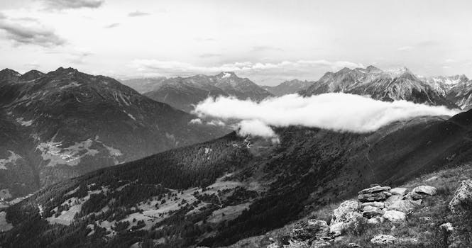 Breathtaking black and white panorama of majestic mountain peaks and valleys under cloudy skies.