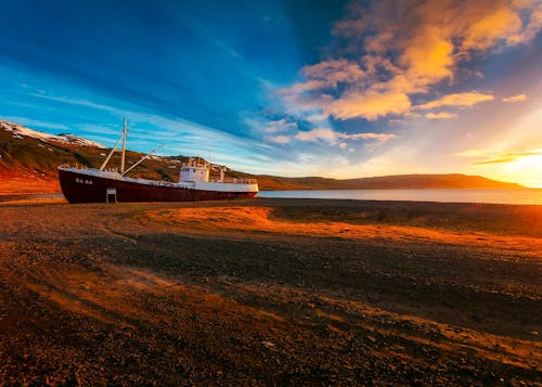 бесплатная бело бордовое грузовое судно на песке Стоковое фото