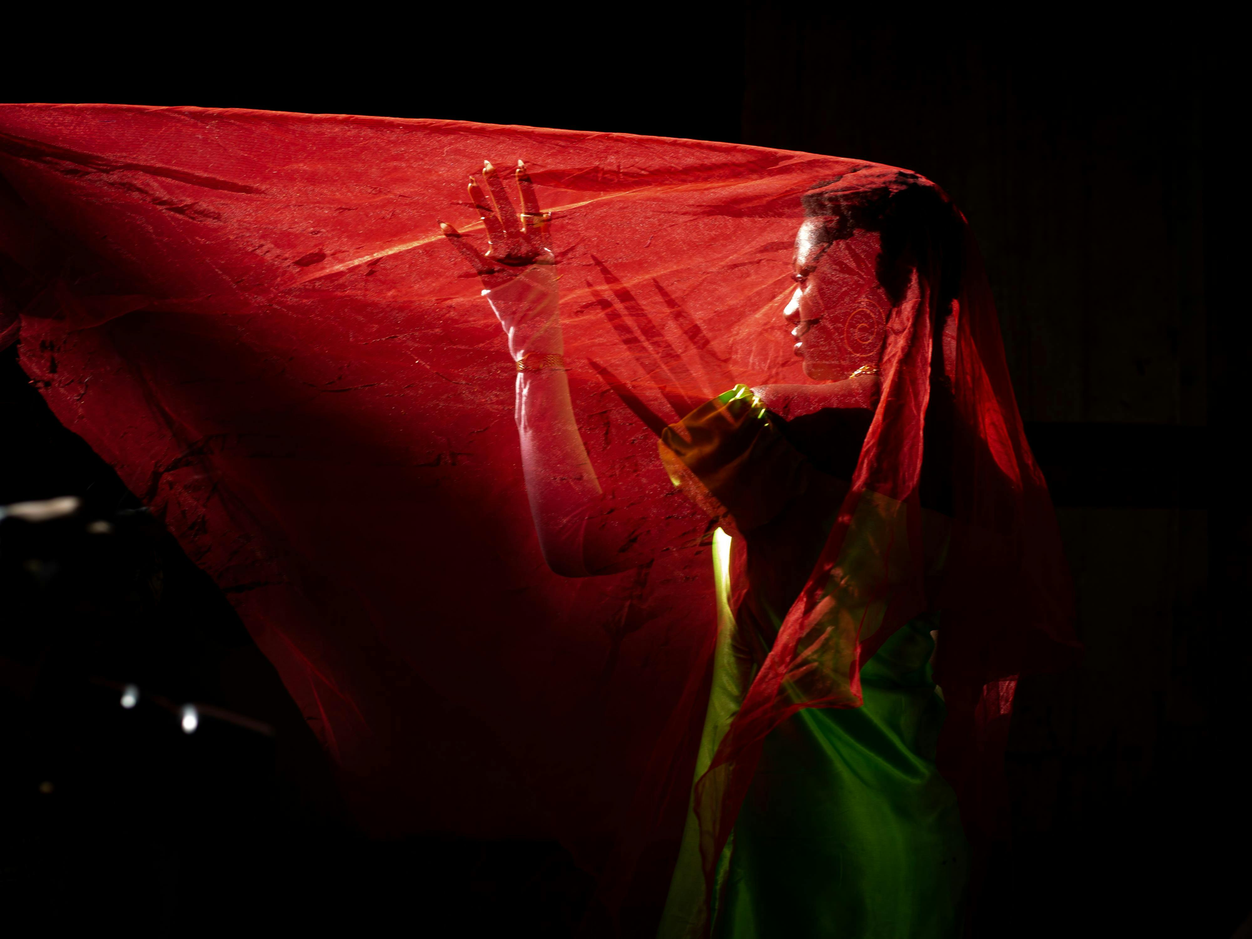 Gratis Un cautivador retrato artístico de una mujer envuelta en un velo rojo, que evoca misterio y elegancia. Foto de stock