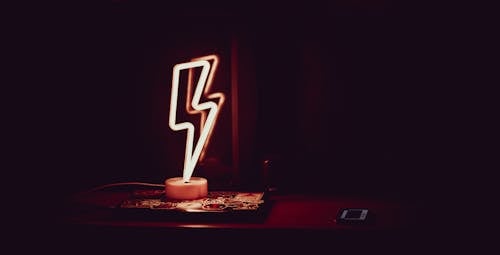 Glowing neon lamp in shape of lightning in dark room