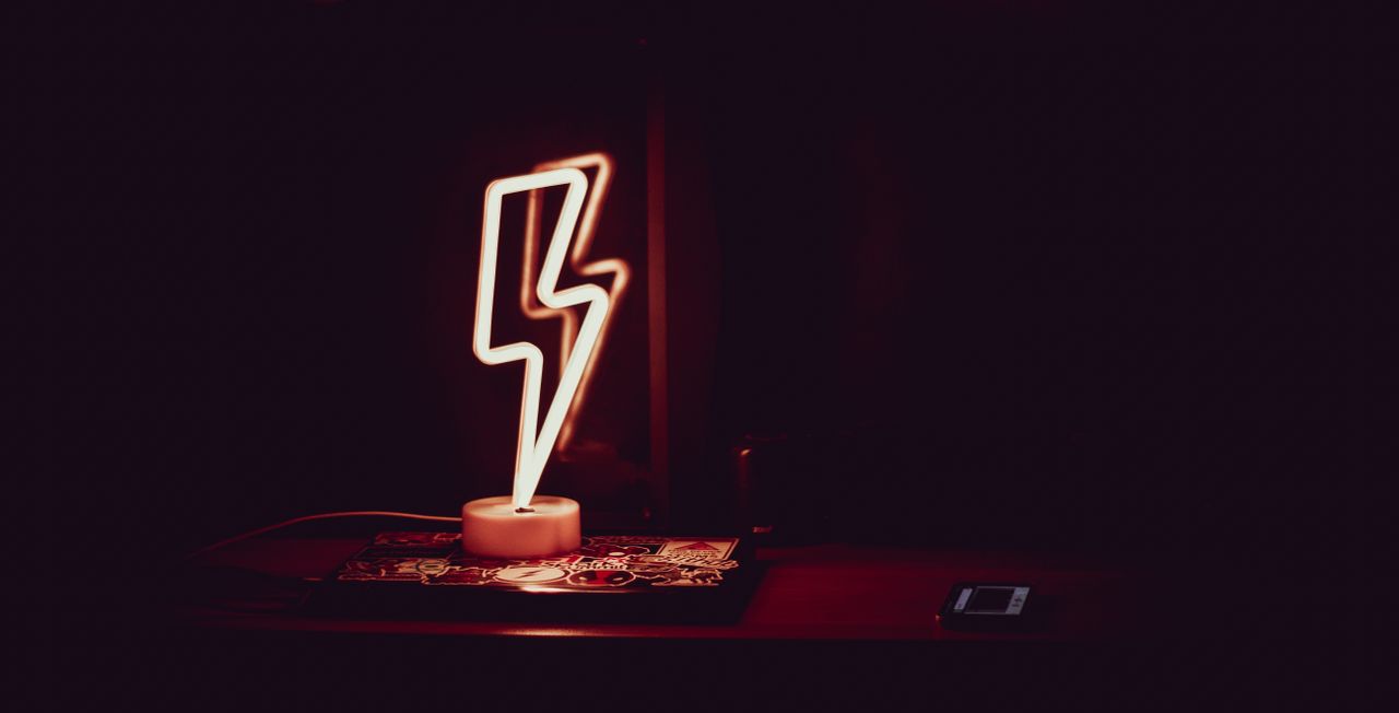 modern neon night light in shape of lightning placed on table and refl