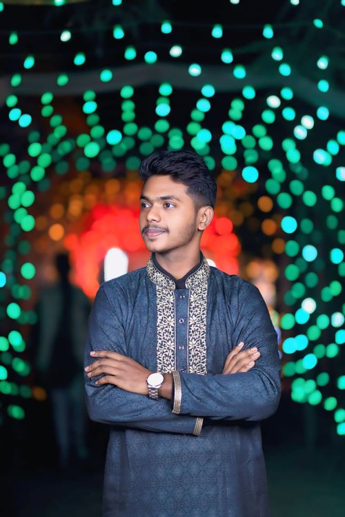 Free A man in traditional clothing stands confidently with colorful bokeh lights in the background. Stock Photo