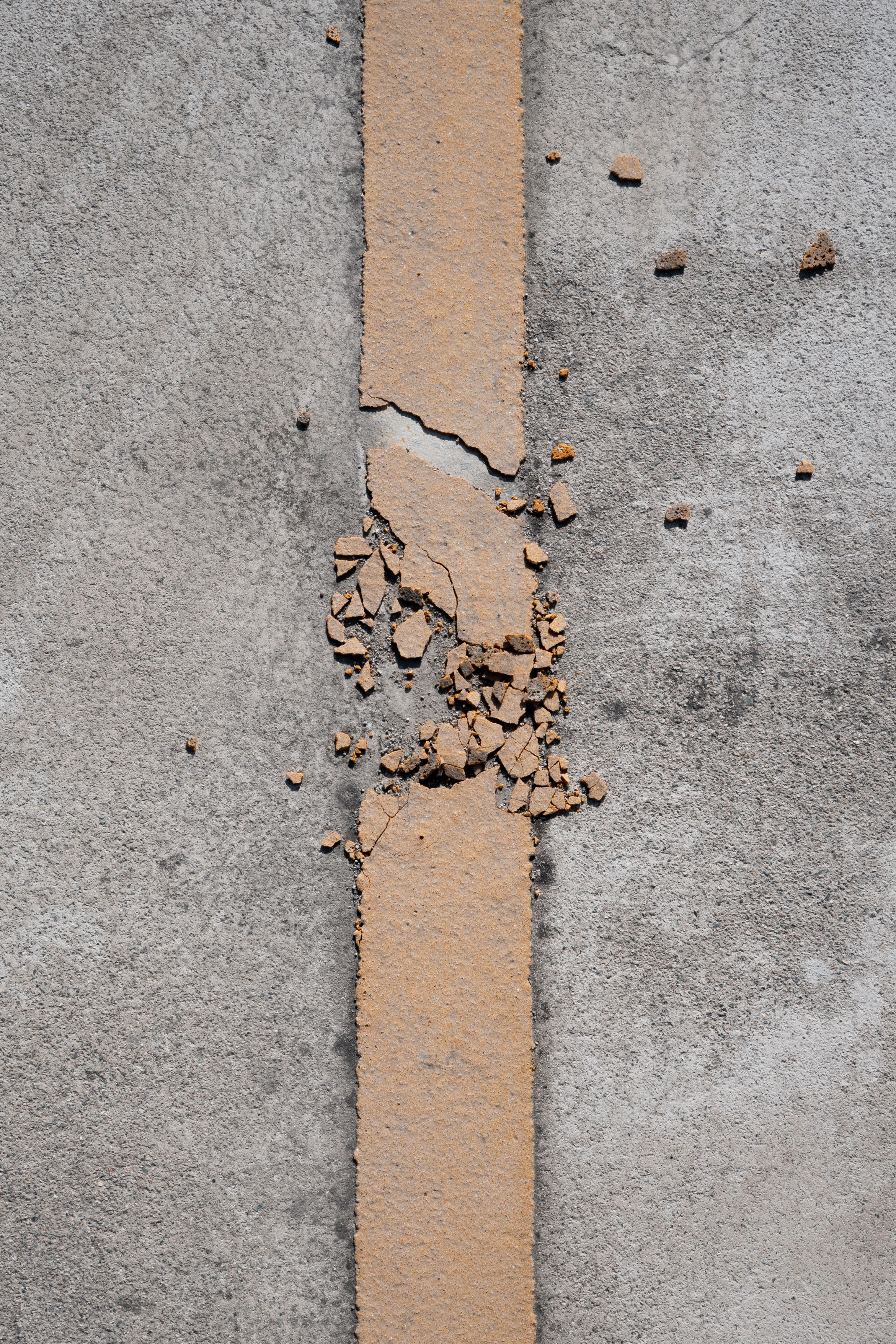 Close-up view of a cracked concrete surface with peeling paint, offering texture and pattern details.