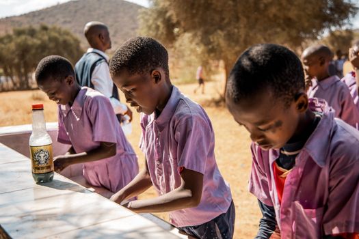 School children washing hands outdoors in Kenya, focusing on hygiene and cleanliness.