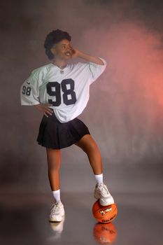 Teenager wearing a sports jersey posing confidently with a basketball indoors.