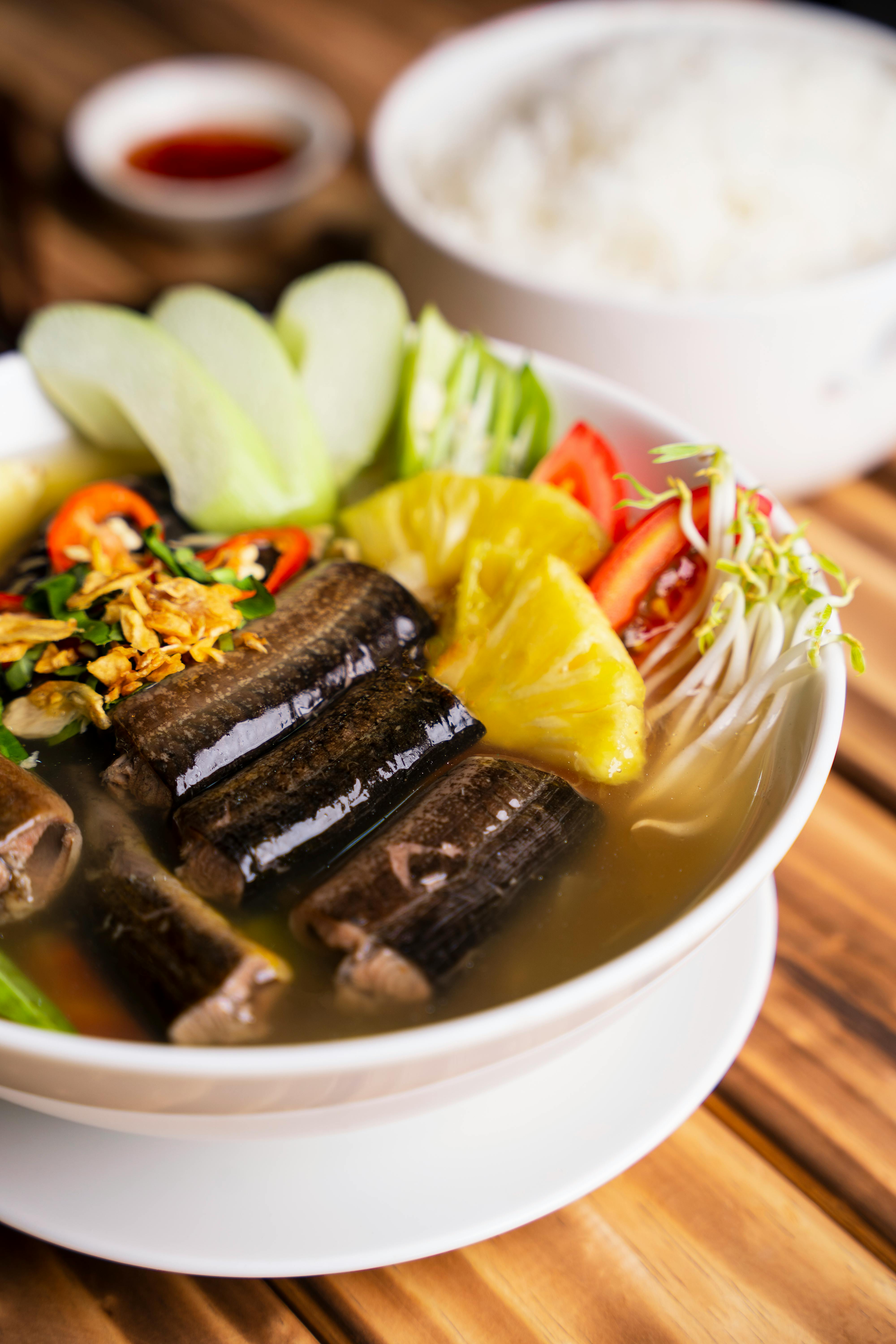 Delicious Vietnamese fish soup with fresh vegetables and a side of rice, highlighting traditional flavors.