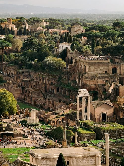 Free A breathtaking aerial shot of the historic Roman Forum in Rome, Italy, surrounded by lush greenery. Stock Photo