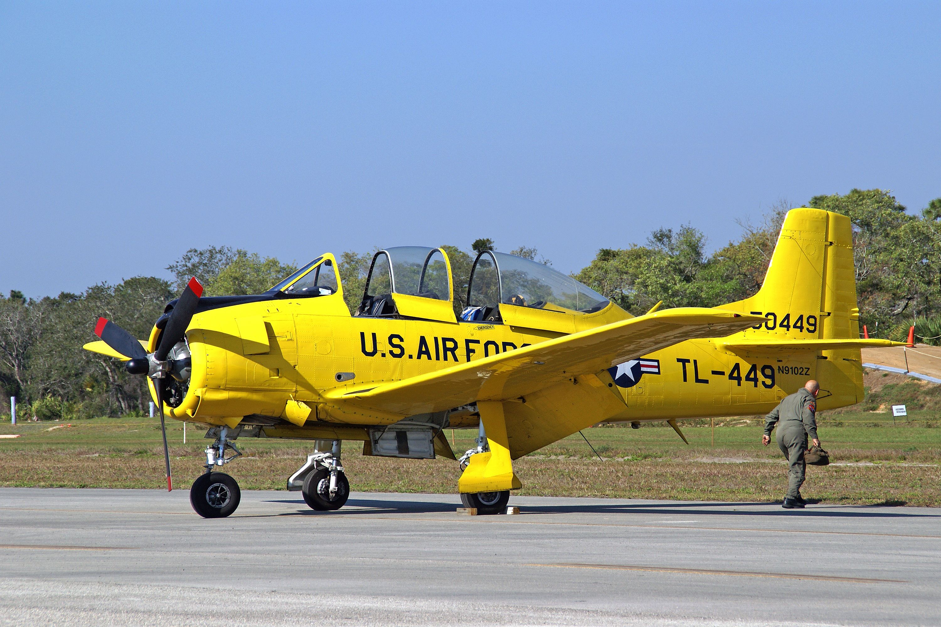 A vibrant yellow T-28 Trojan aircraft on an airfield in Titusville, Florida.