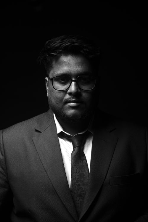 Free Moody black and white portrait of a man in a suit and glasses, captured in low light. Stock Photo