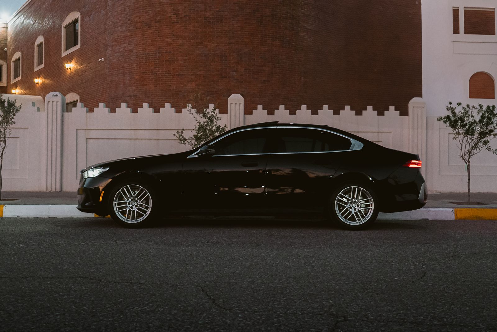 black luxury sedan parked on a street at night