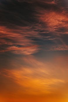 Stunning sunset with dramatic clouds and vibrant hues of orange and red, captured in a serene sky.