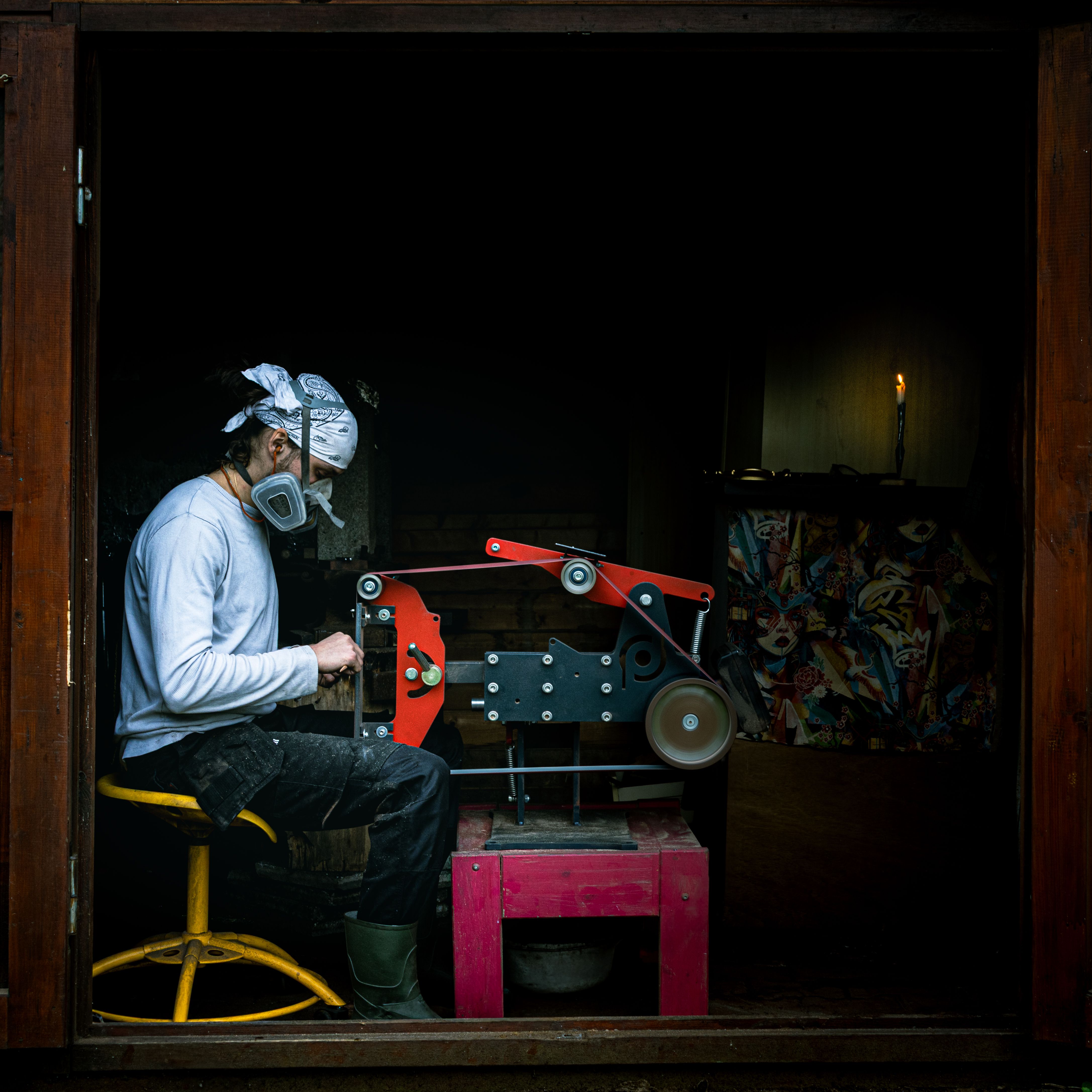 An artisan in Gradignan, France, working with a grinding machine in a dimly lit workshop.
